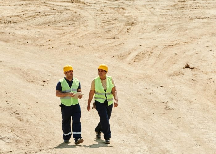 Workers Wearing Safety Vest and Hard Hat Walking on the Dry Ground